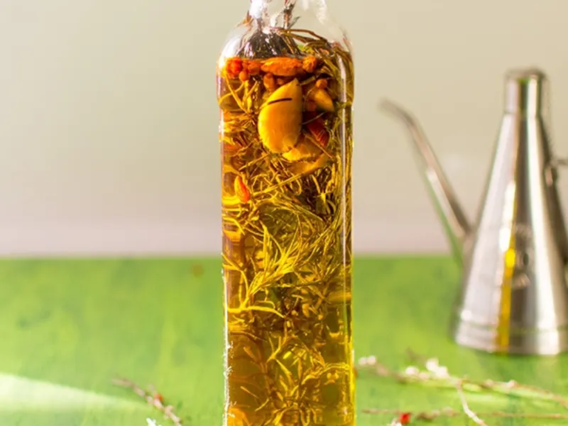 Bouteille de purée de piment maison infusée d’ail et d’épices, huile dorée et herbes visibles, prête à utiliser pour une recette purée de piment maison.